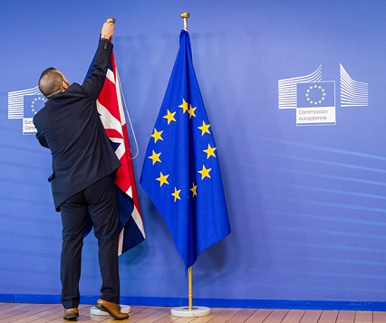 An EU official hangs the Union Jack next to the European Union flag at the VIP entrance at the European Commission headquarters in Brussels on Tuesday, Feb. 16, 2016. British Prime Minister David Cameron is visiting EU leaders two days ahead of a crucial EU summit. (AP Photo/Geert Vanden Wijngaert)